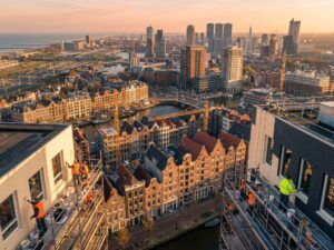 Luchtfoto van Nederlandse schilders op steigers bij historische grachtenhuizen en moderne gebouwen in de Randstad